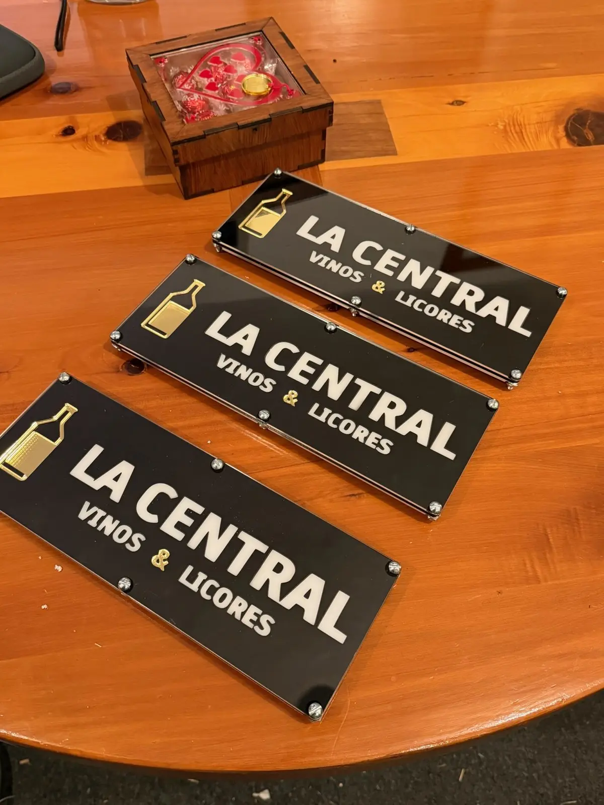Tres letreros de acrílico negro y dorado de La Central Vinos & Licores