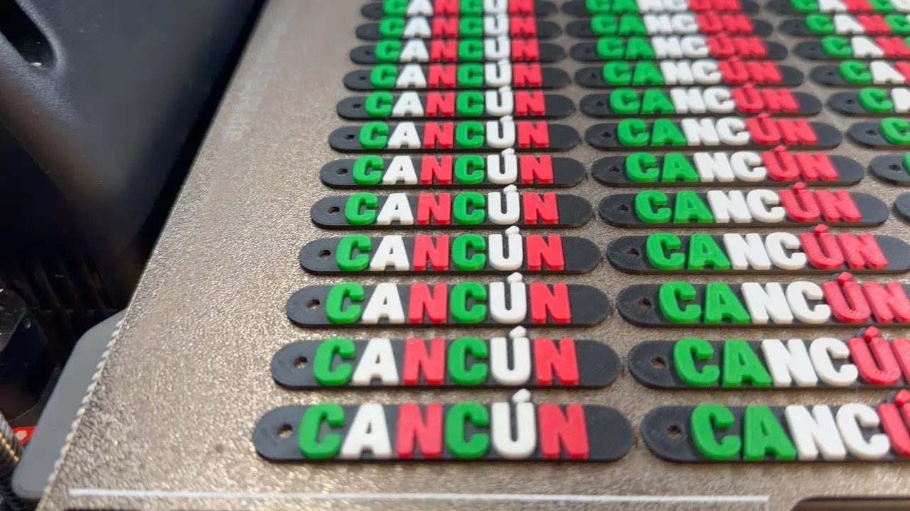 Llaveros Cancún tricolor impresos en 3D en serie sobre la cama de impresión